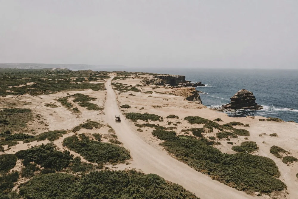 Sandy coastal road running towards the cliffs and Atlantic Ocean along Portugal’s Costa Vicentina