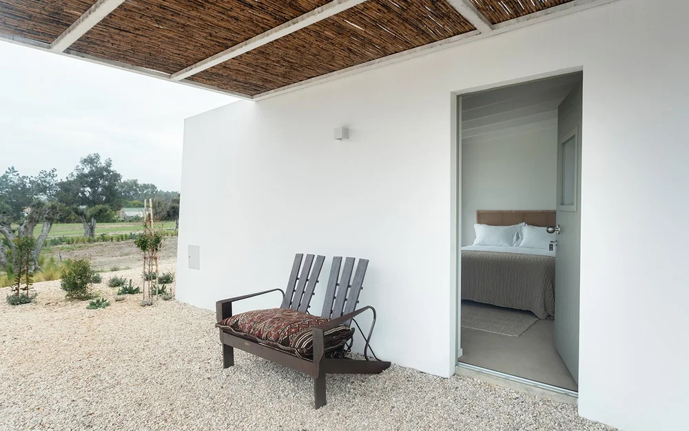 Covered terrace outside Junior Suite 5 with a rocking chair and landscape view at Amaria