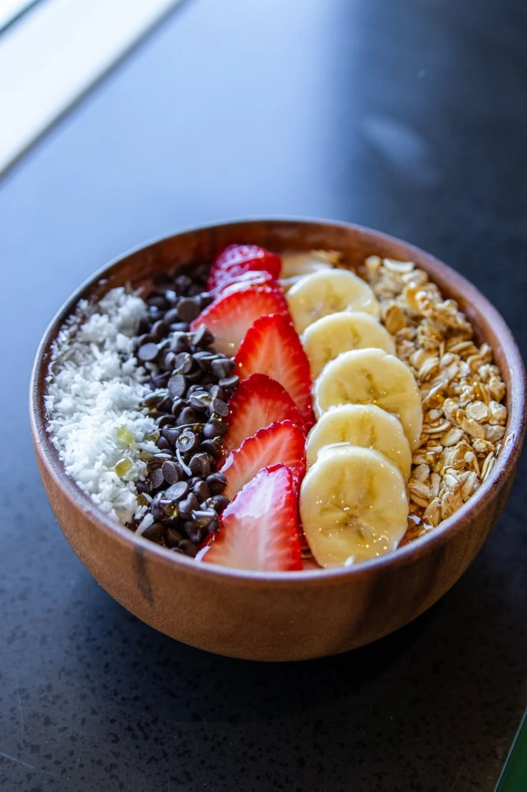 Açaí bowl topped with coconut, chocolate chips, strawberries, banana and granola