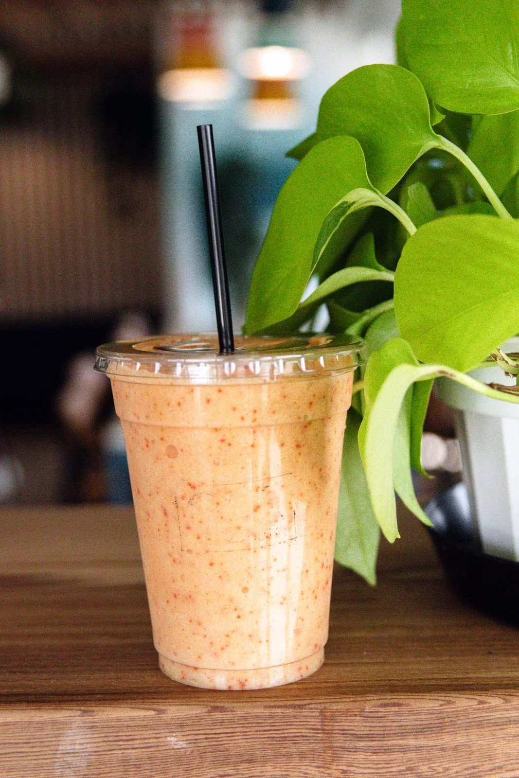 Strawberry mango smoothie next to a plant