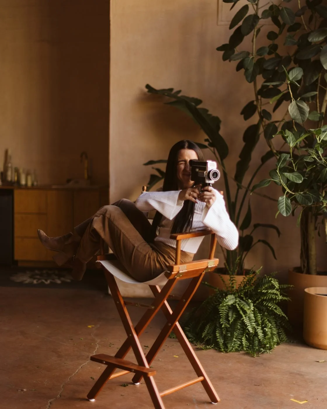 Kaylee in a director's chair, filming with a vintage camera