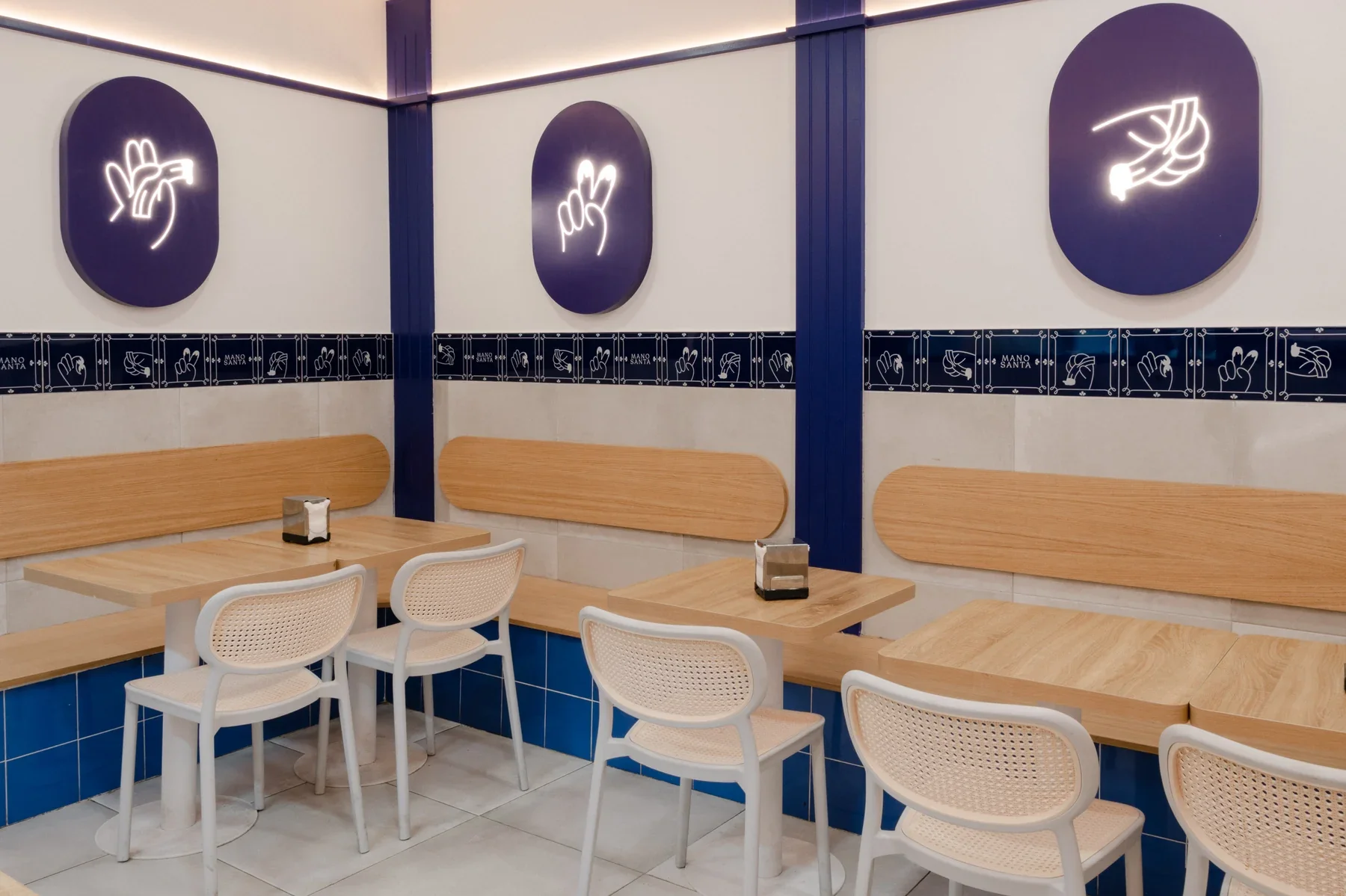 Mesas de madera, azulejos e ilustraciones de manos en el interior de Manosanta