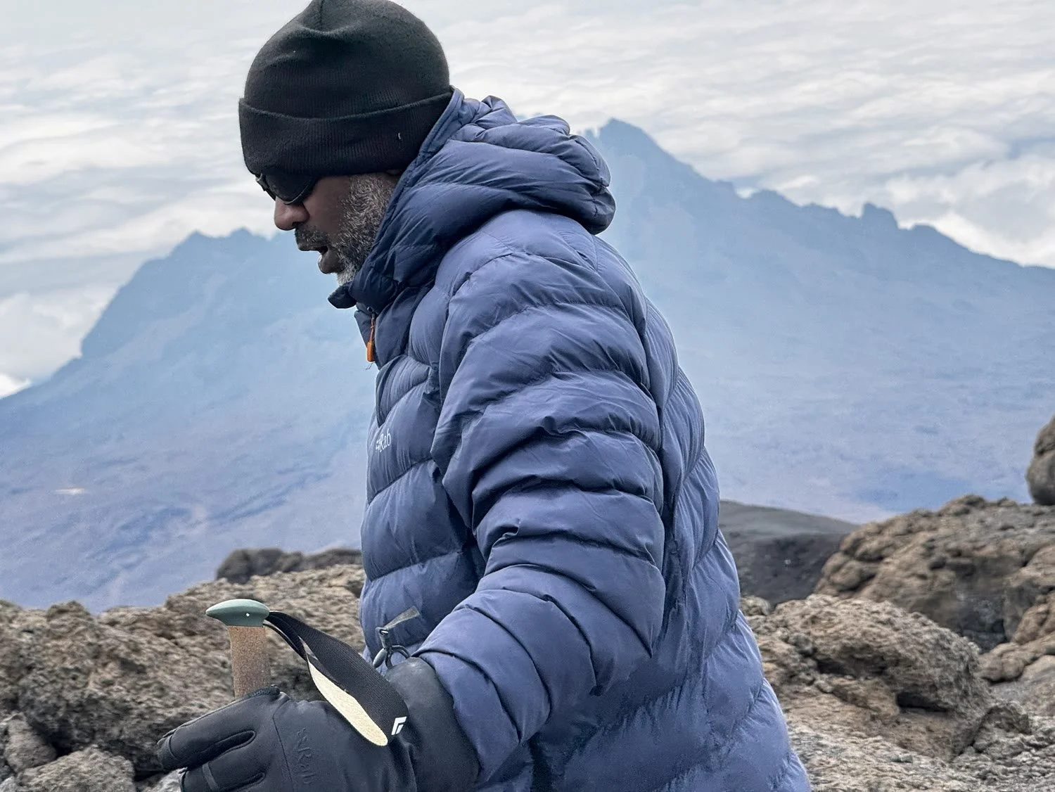 Luciano on summit morning with his poles, head down, Mawenzi behind