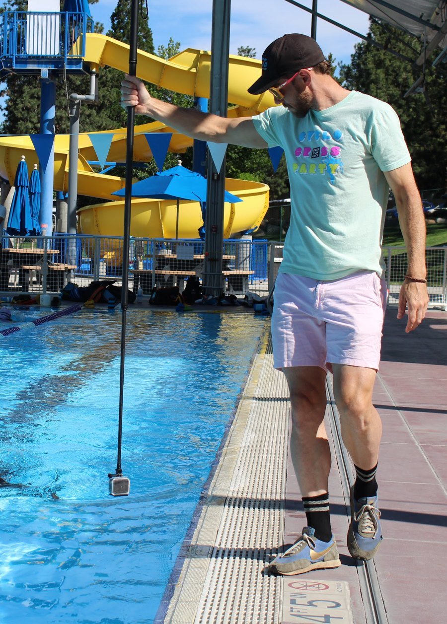 Chris filming a swimmer's stroke from the pool deck