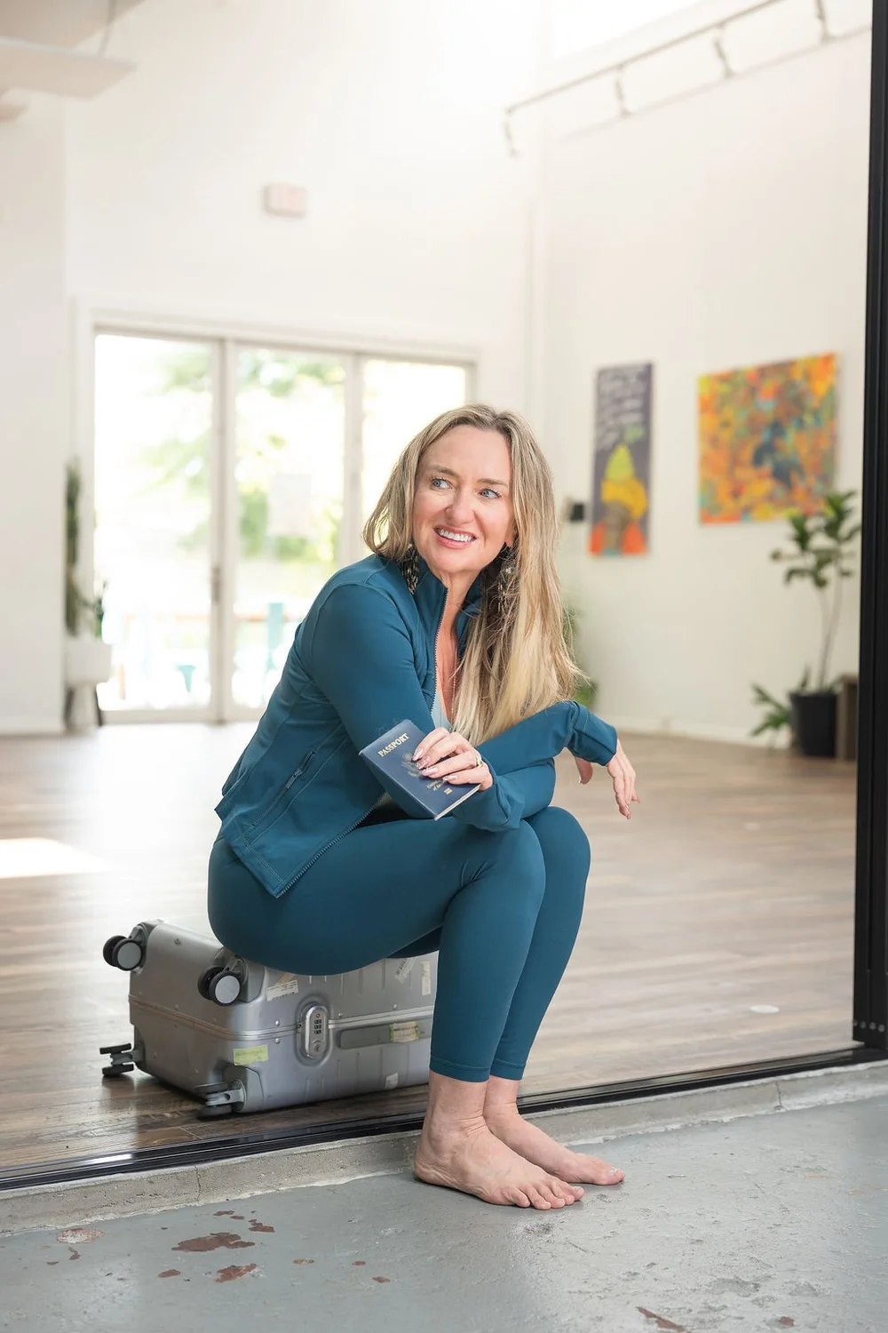 Shelley Carroll, founder of DDY Travels, laughing while sitting on her suitcase