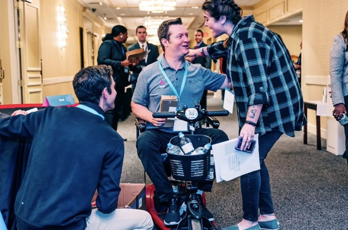 Participants, one using a mobility scooter, talk with employers at a MassAbility career event