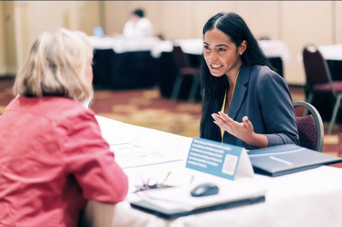 A job seeker talks with an employer across a table at a career event