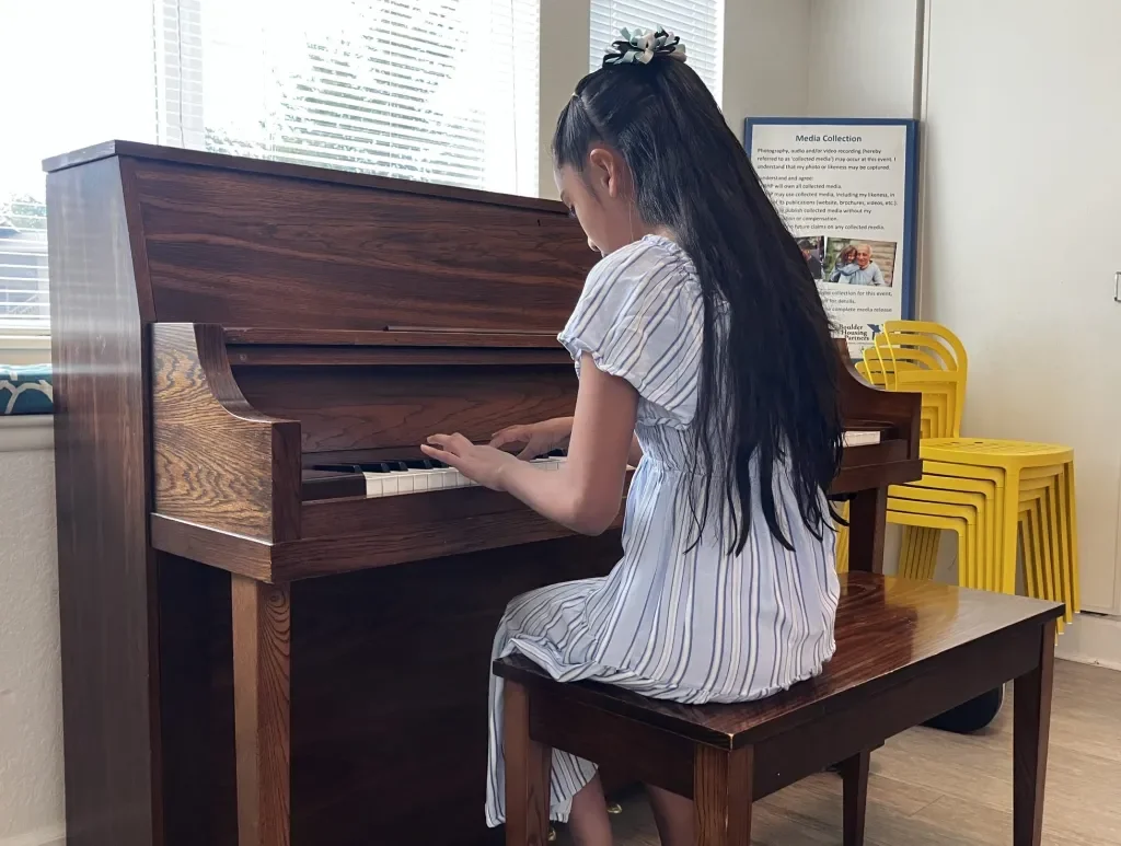 A student practicing piano at a Boulder Housing Partners community