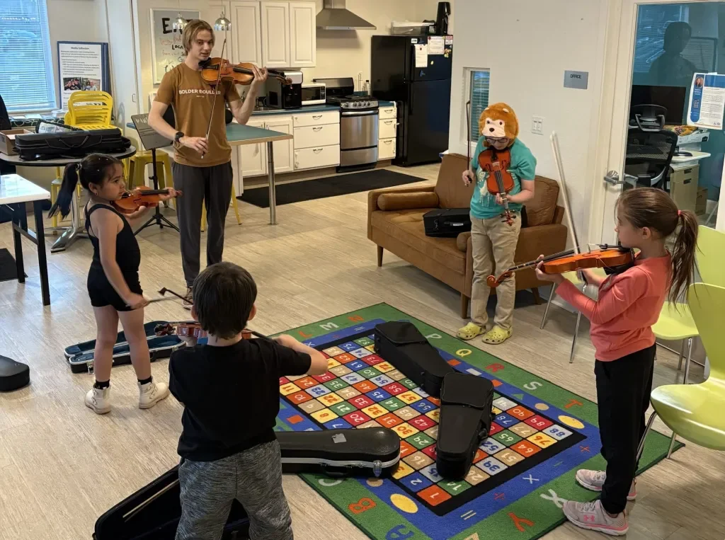 Group violin lesson at a Boulder Housing Partners community