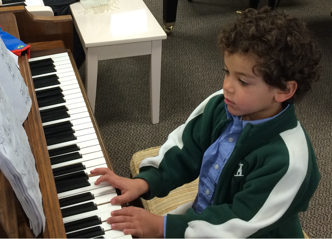 A student learning piano on one of Parlando's on-site pianos