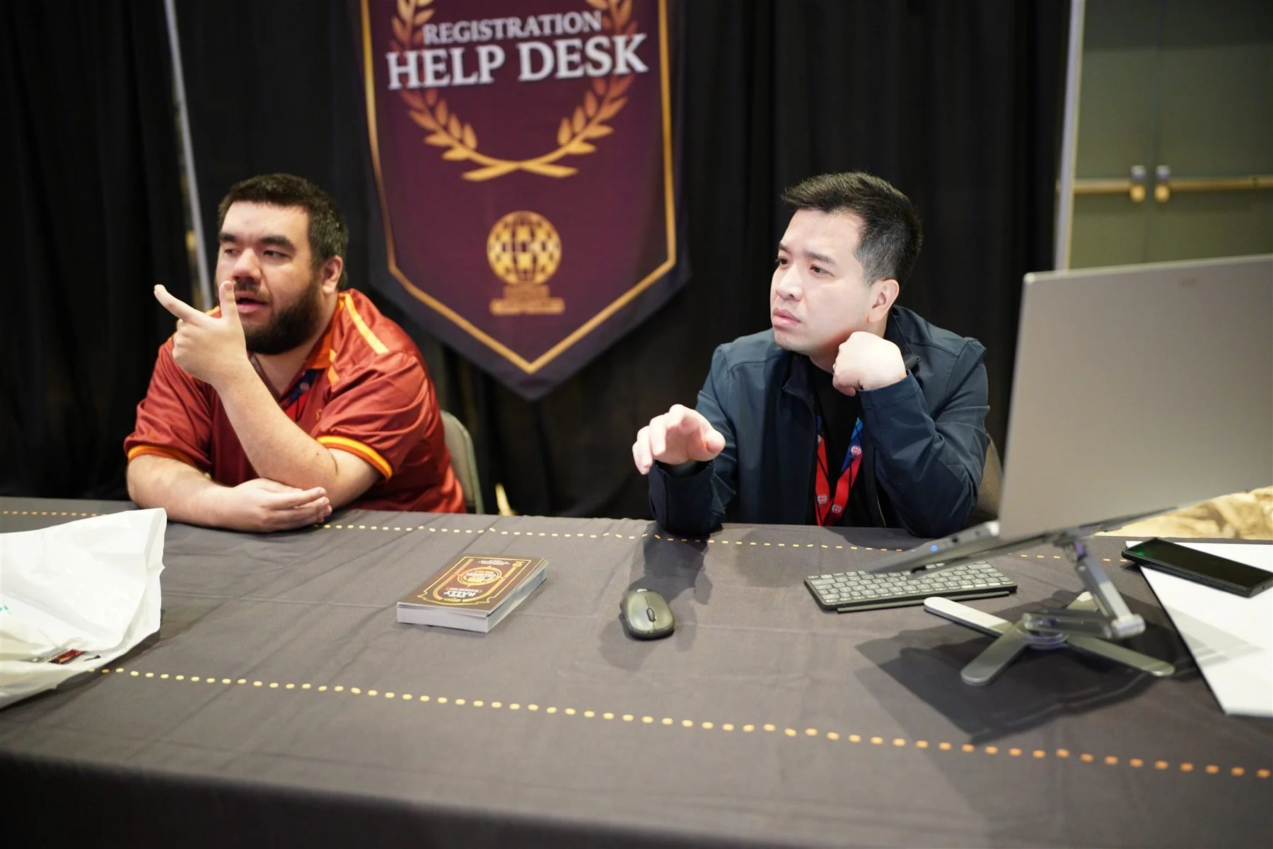 Two team members at the Dallas Registration Help Desk beneath the burgundy and gold event banner