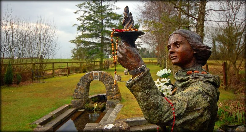 Stone arch, flowing water and statue of Brigid at her holy well in Kildare