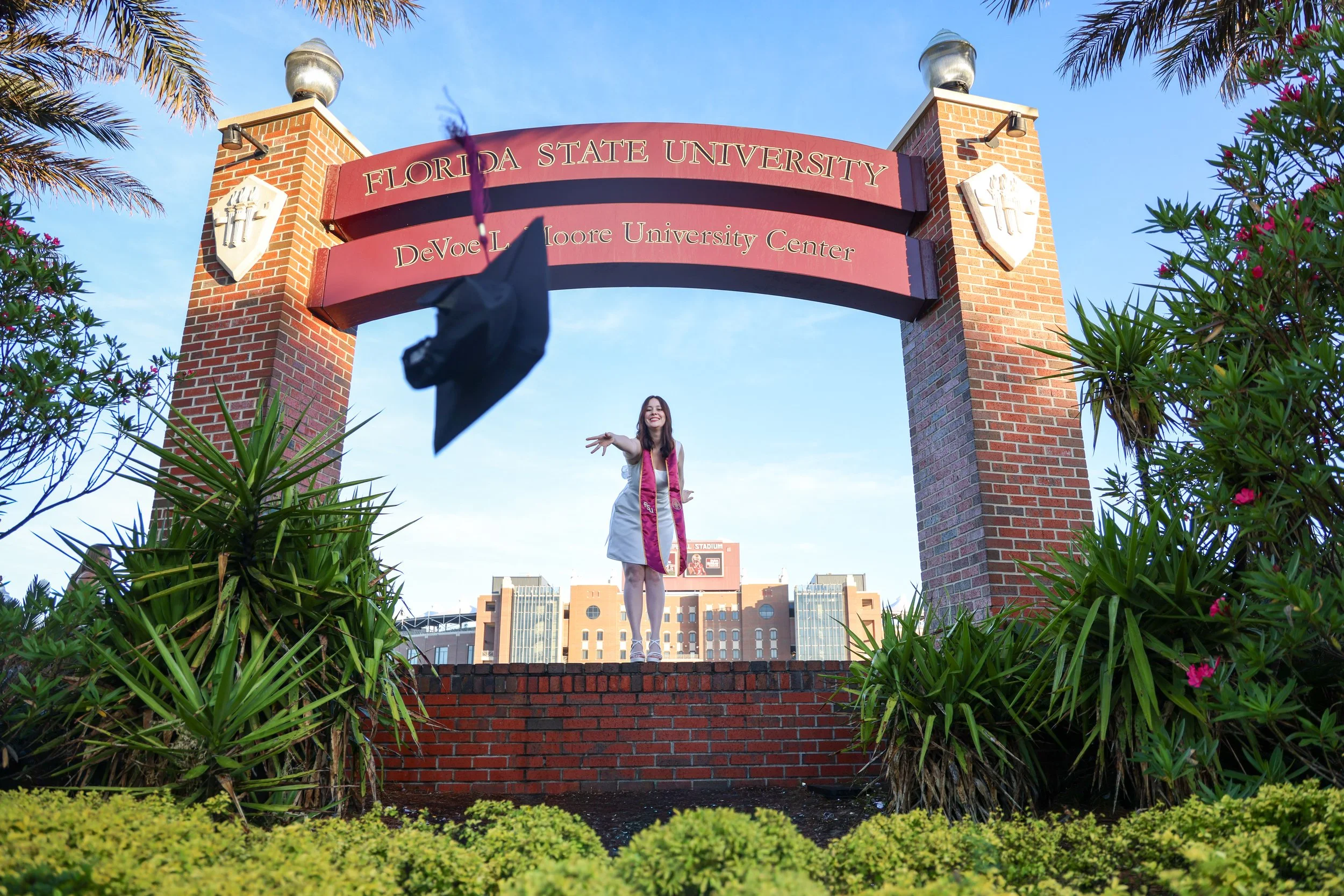 FSU graduate in cap and gown celebrating at Westcott Fountain during golden hour in Tallahassee