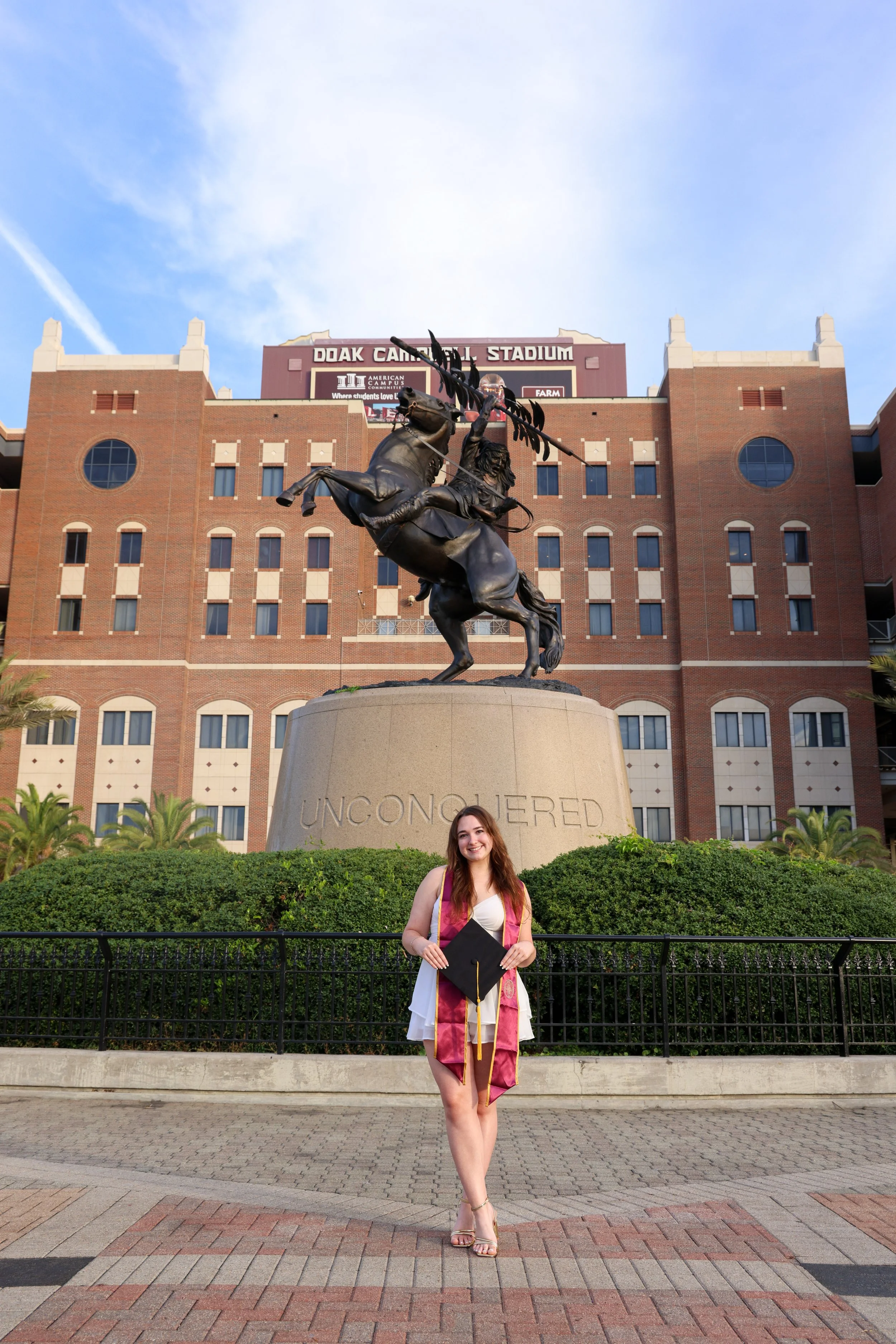 FSU graduate at the Unconquered Statue, an iconic Florida State graduation photo spot