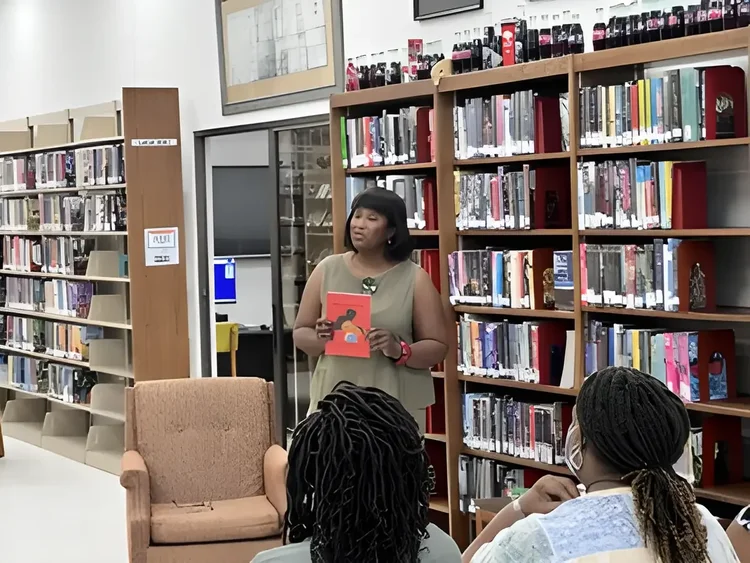 Daphne Tillman Perry holding one of her books while speaking at a library