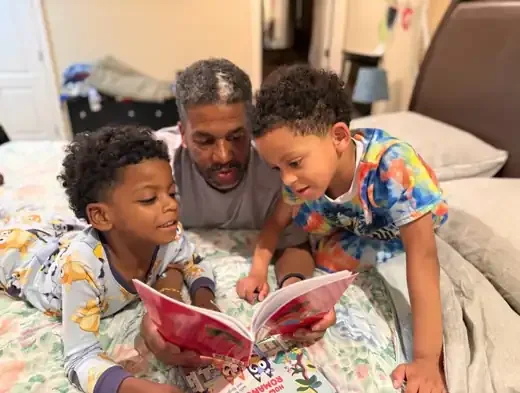 Wesley and Kyrie reading a Daphne Tillman Perry book with their grandfather