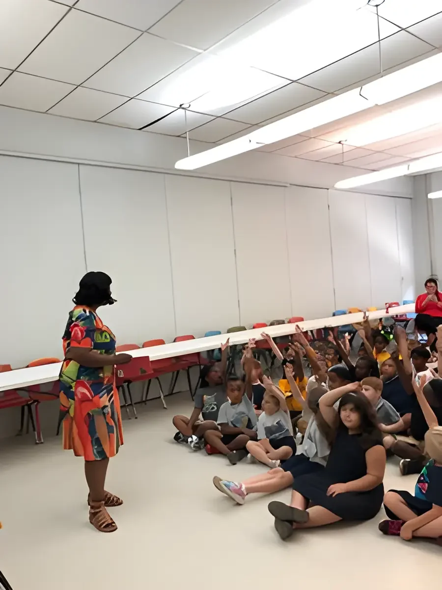 Daphne Tillman Perry speaking to a large group of children with their hands raised