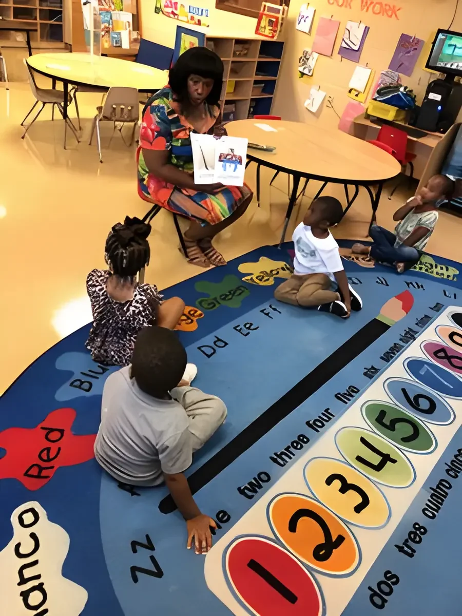 Daphne Tillman Perry seated on a classroom rug reading to preschool children
