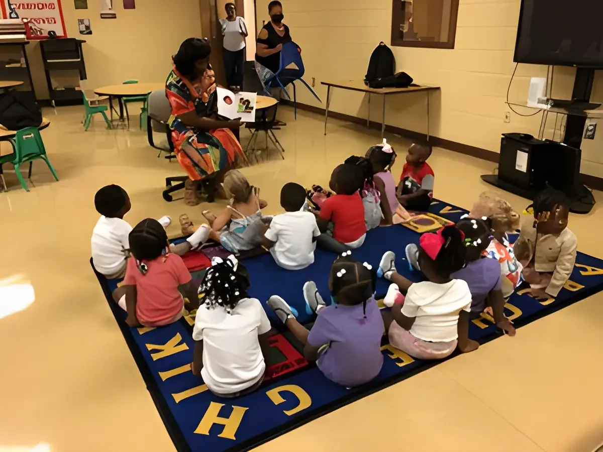 Daphne Tillman Perry reading aloud to preschoolers seated on a classroom rug