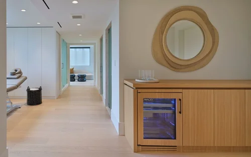 Couloir avec meuble bas en bois et réfrigérateur à porte vitrée, miroir au cadre de forme organique