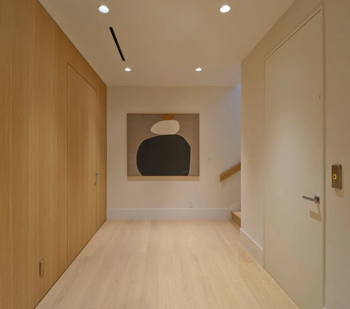 Dégagement avec mur en boiserie et porte affleurante fermée, tableau aux formes sombres sur fond clair