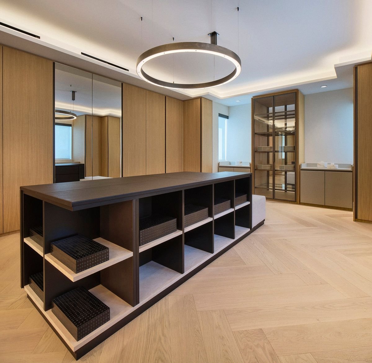 Îlot sombre à casiers ouverts avec boîtes noires, suspension en anneau, armoires en bois, portes miroir et vitrine éclairée