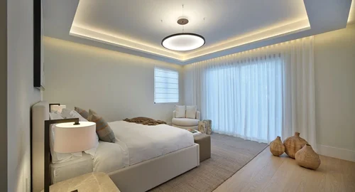 Chambre avec suspension ronde, plafond à éclairage indirect et voilages toute hauteur