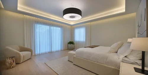 Chambre avec suspension noire, rideaux clairs toute hauteur et fauteuil blanc