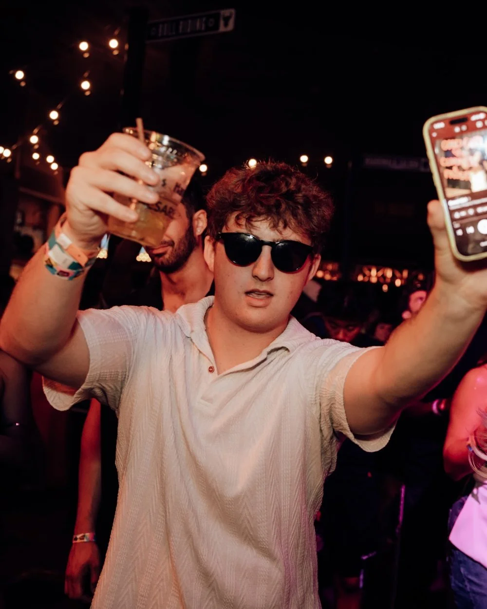 Guest raising a drink and filming on his phone at a Fame-promoted party at The West, Caesars Atlantic City