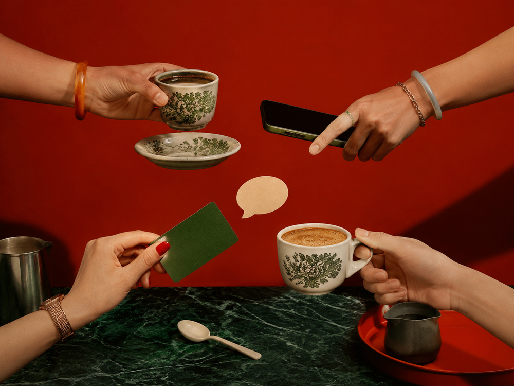 Hands meeting over coffee with a card, phone and a speech bubble, the start of a Kopi Date Brew