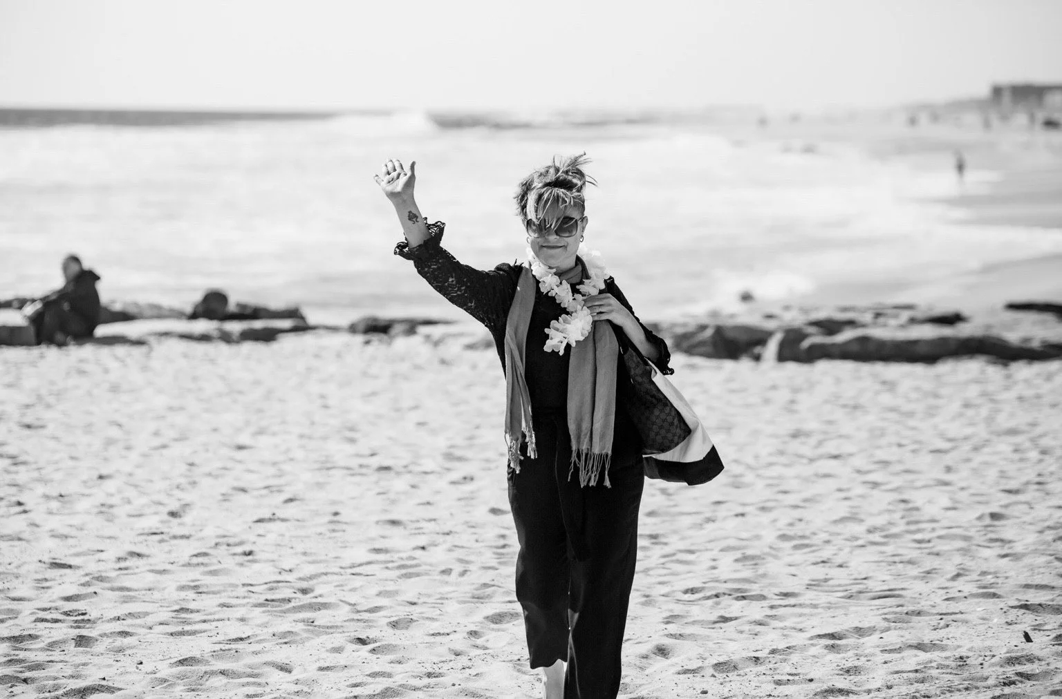 Black-and-white beach portrait of a woman waving.