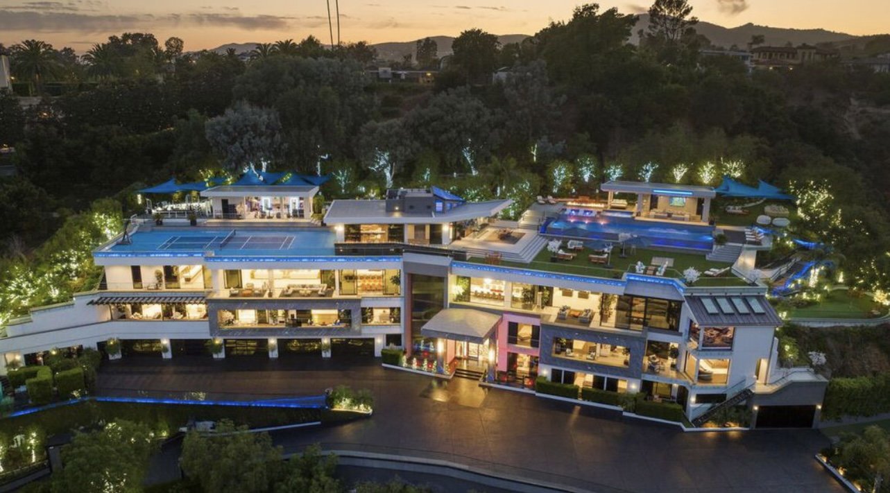 Aerial view of luxury estate with professional outdoor lighting — warm white landscape and holiday lights at twilight, Los Angeles