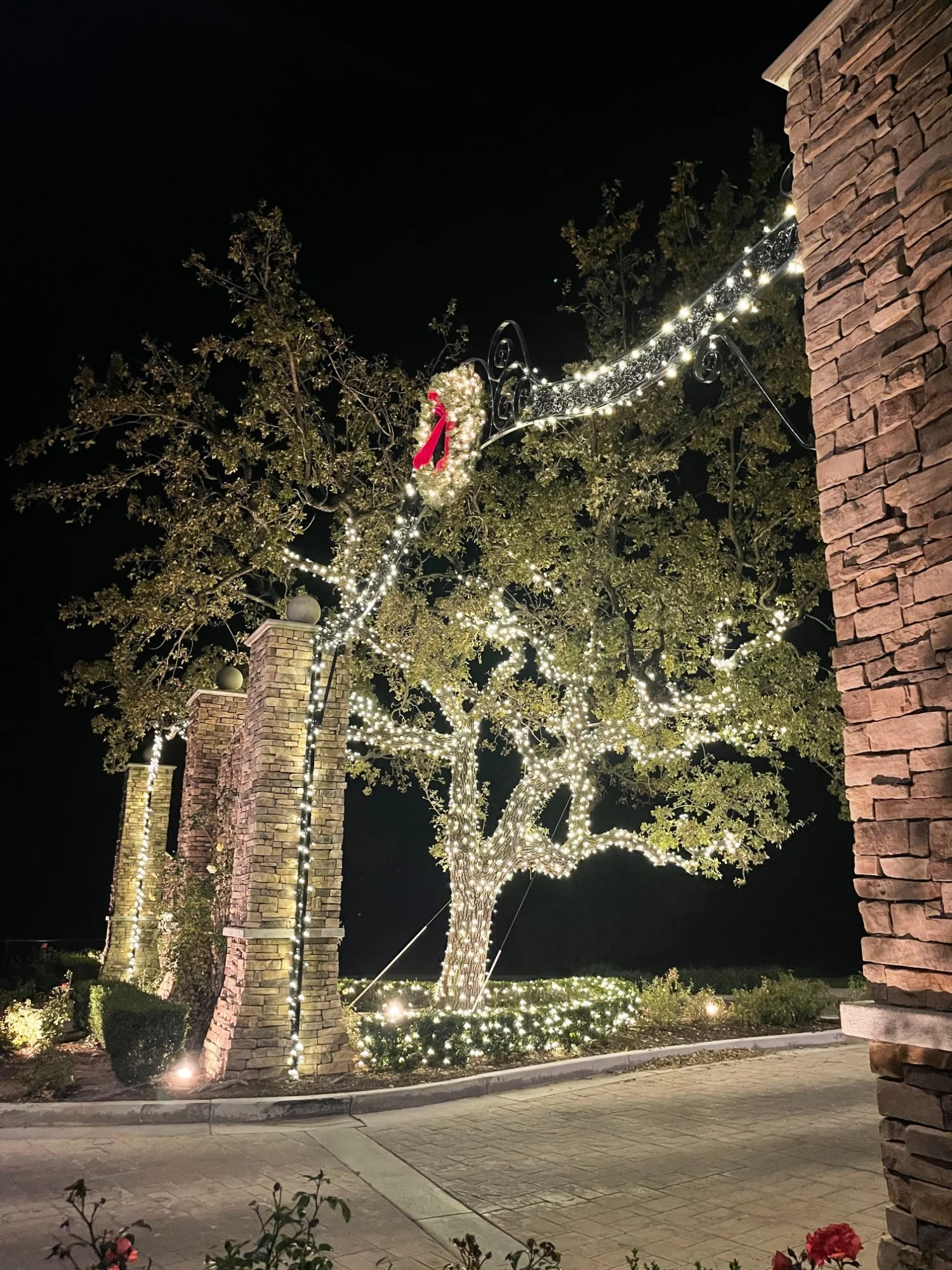 Holiday lighting on HOA entry gate with wreath — professional community Christmas lights Los Angeles