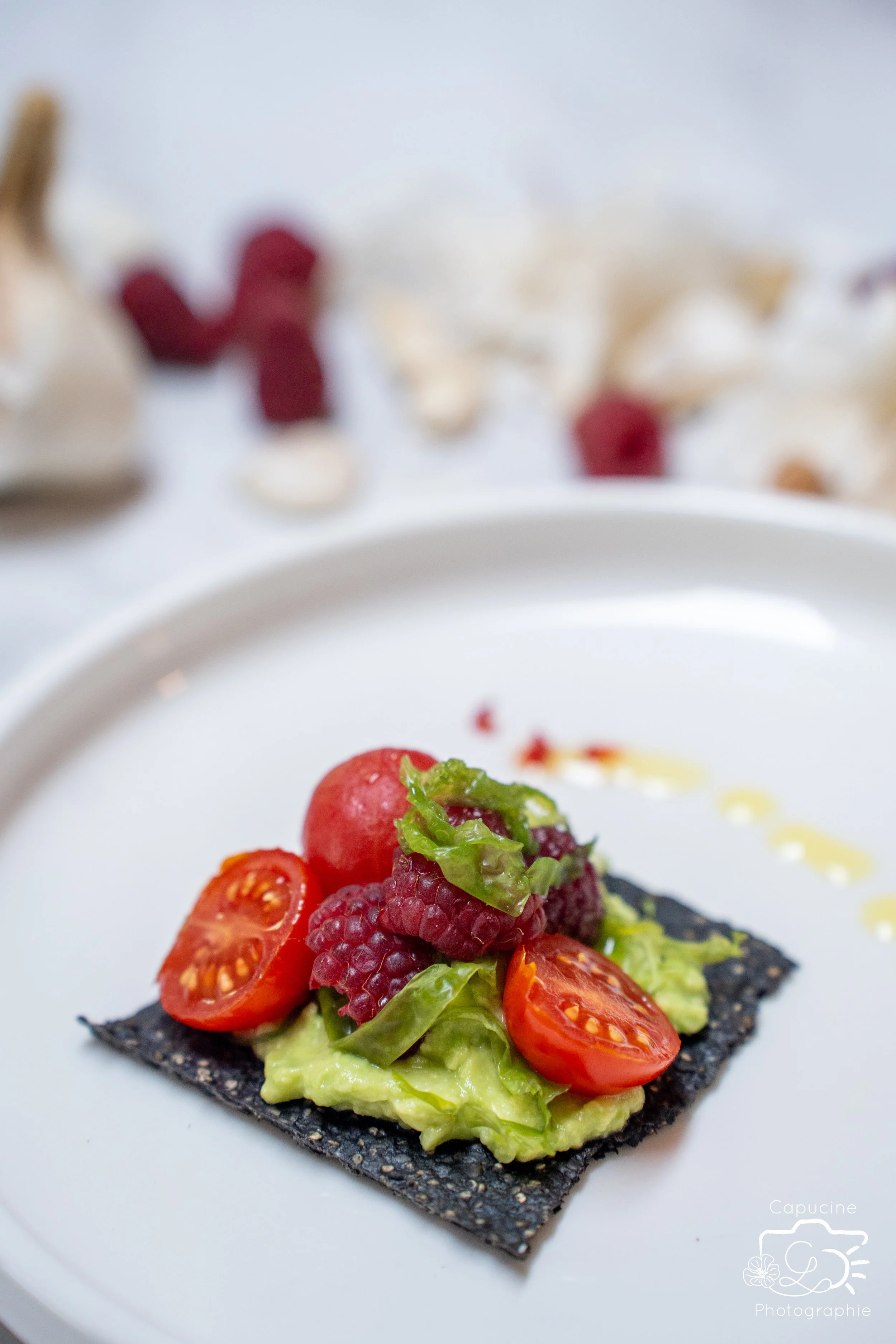 Cracker noir aux algues, avocat, tomates et framboises