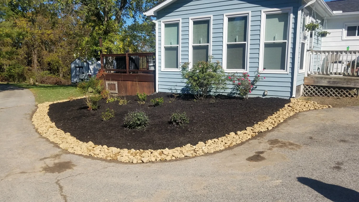 Cleaned landscape bed with mulch and stone edging beside a home