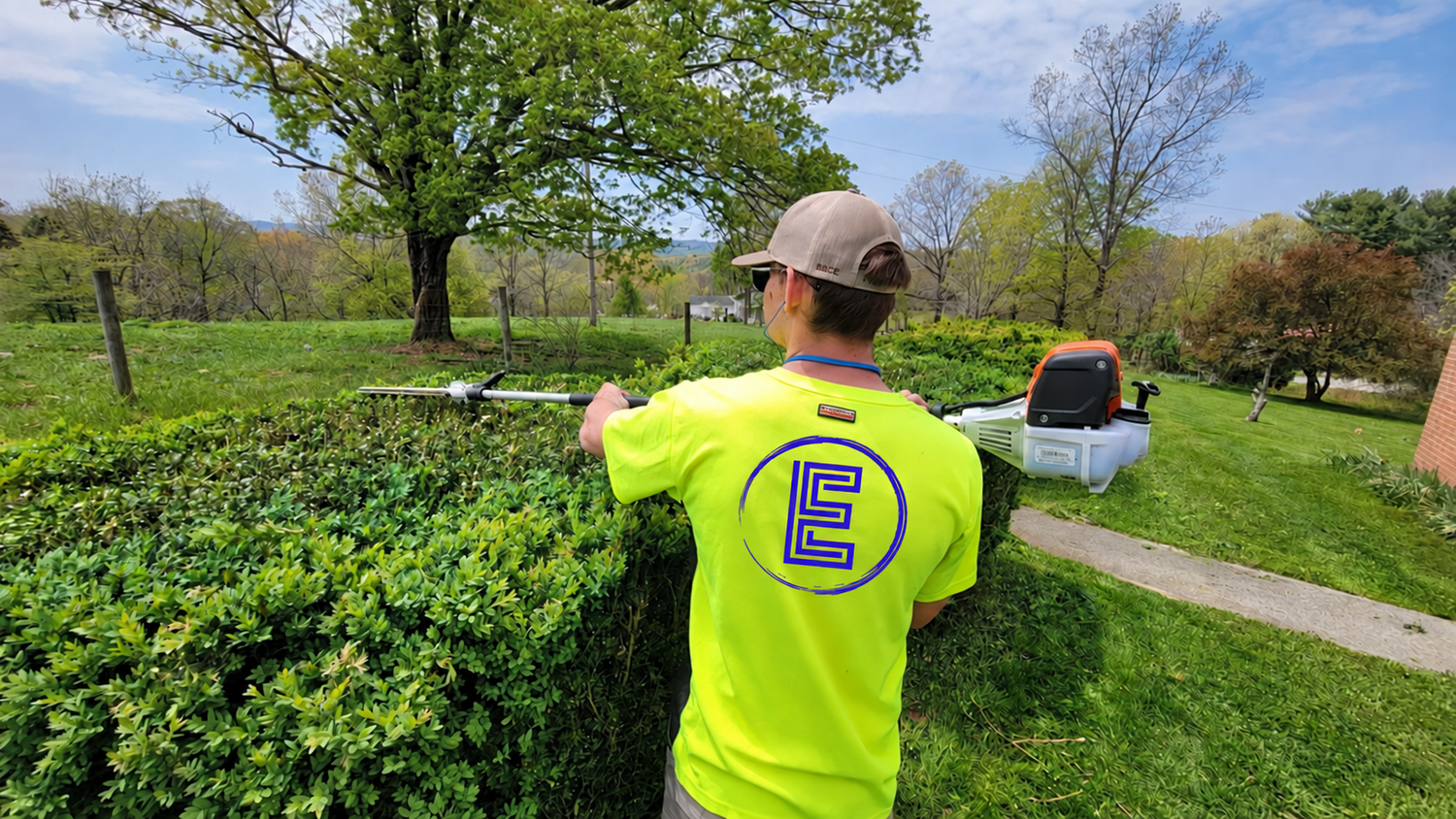 East Coast Lawns crew member trimming a hedge in a branded shirt