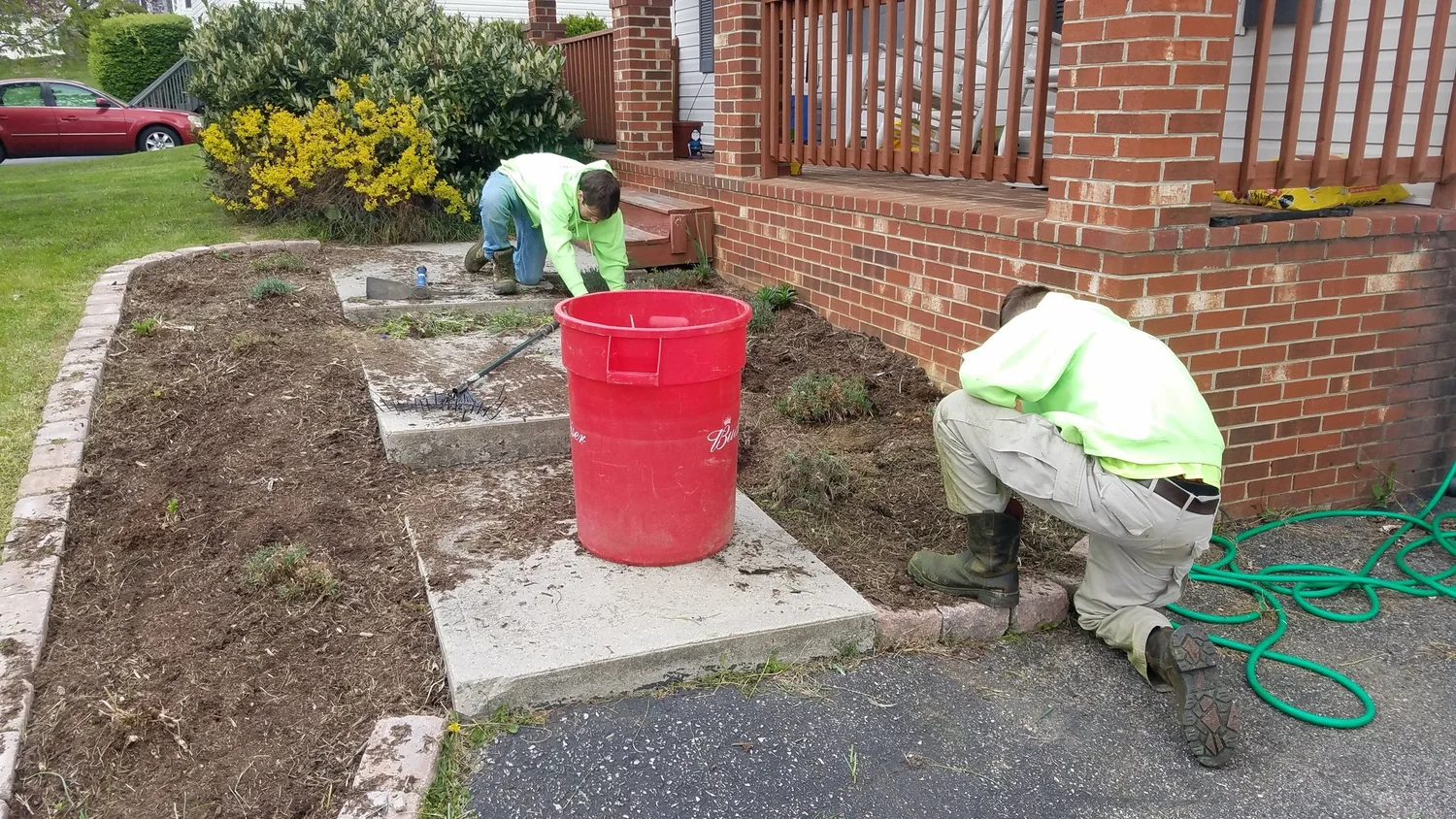 East Coast Lawns crew working in landscape beds beside a front porch