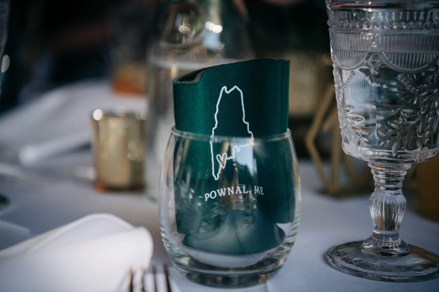A custom Pownal, Maine pint glass set at a wedding dinner table in the barn