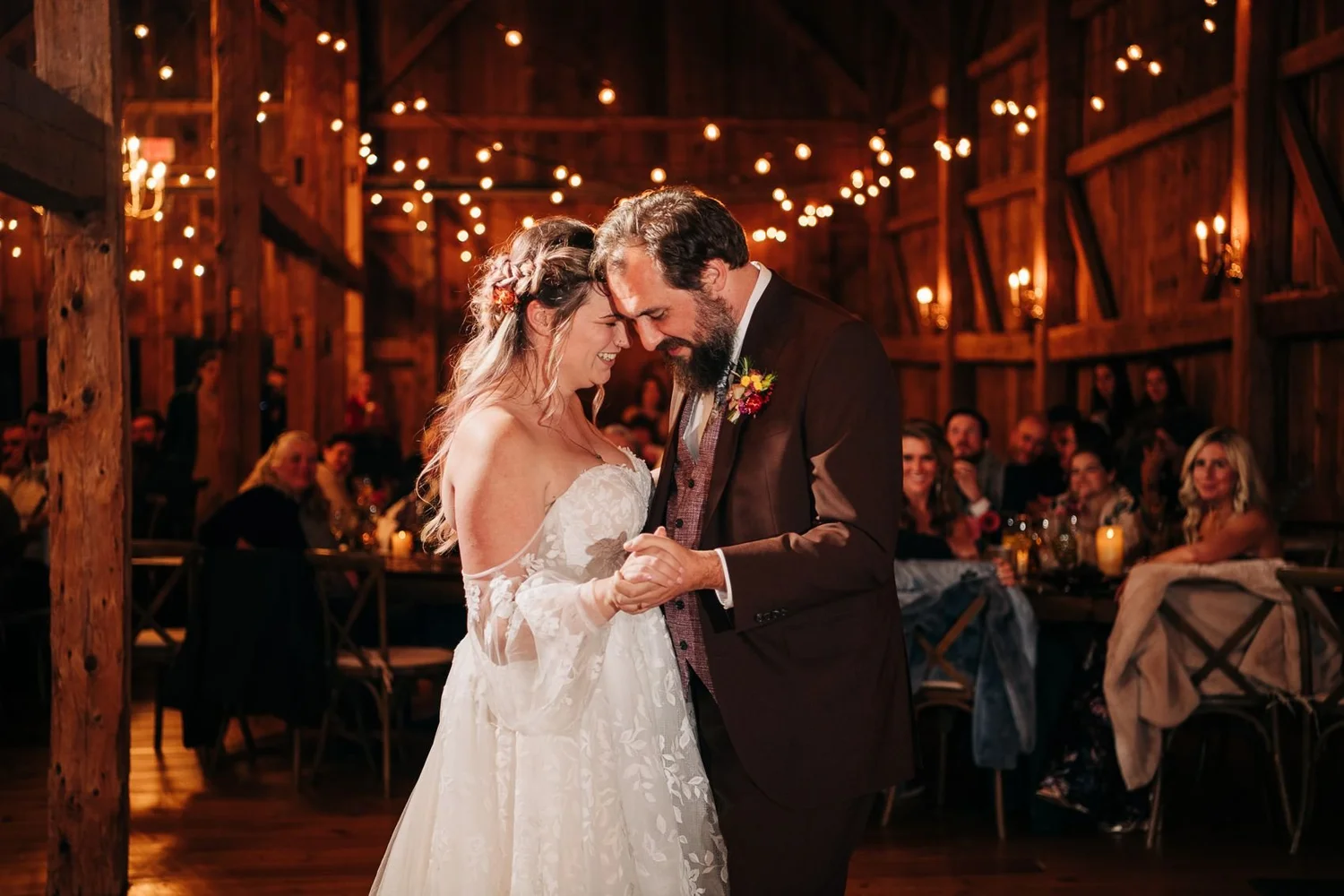 A bride and groom sharing a quiet moment under string lights inside the barn at William Allen Farm