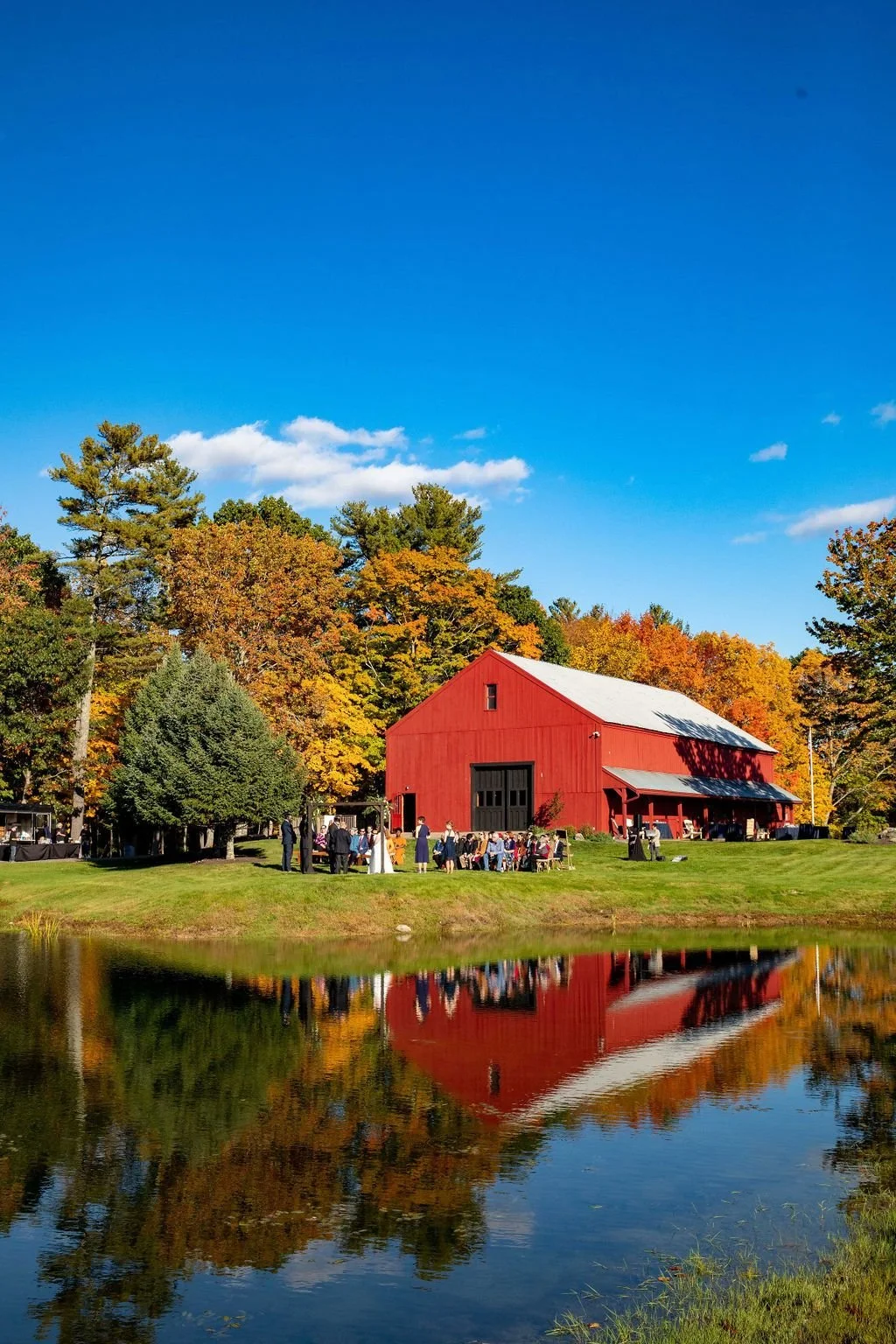 The red barn reflected in the pond with peak fall foliage