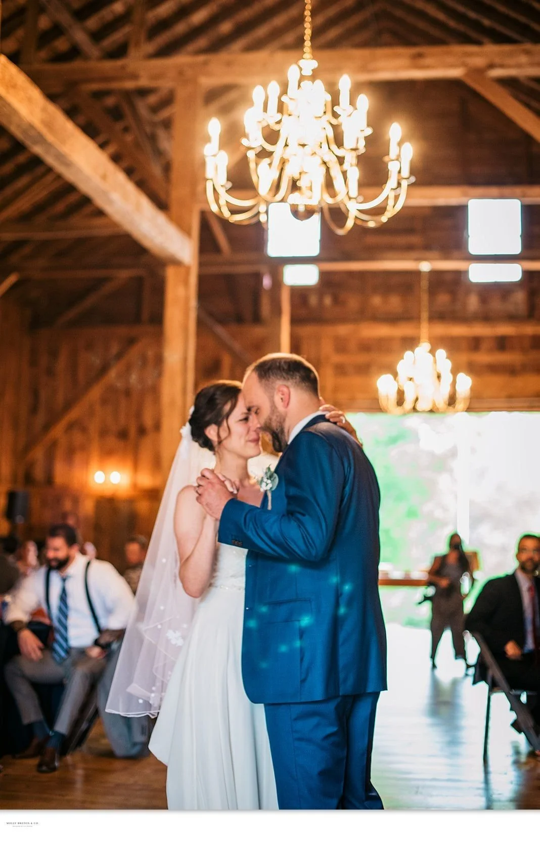 A first dance kiss under the chandeliers in the barn