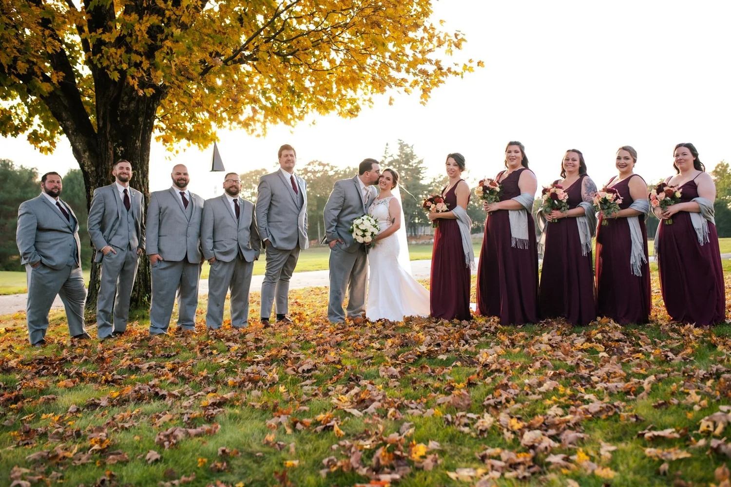 A wedding party gathered on the fall lawn at William Allen Farm in Pownal, Maine