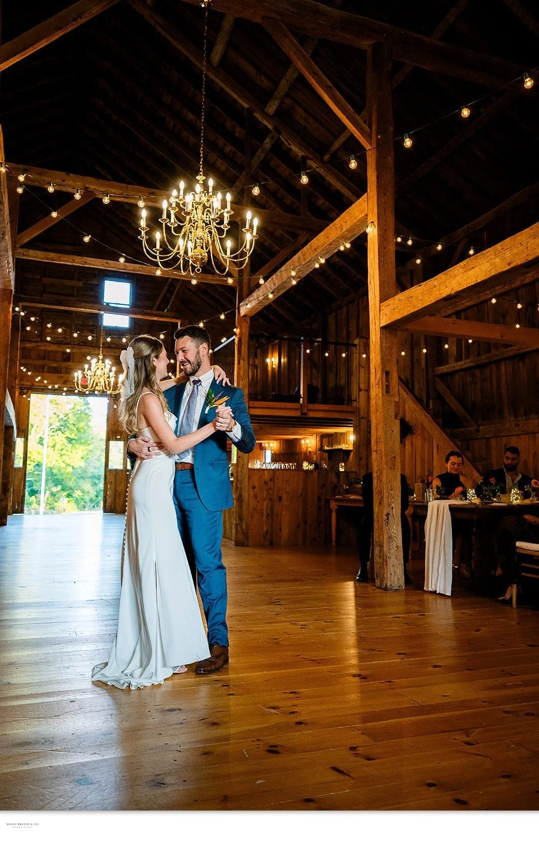 A first dance under the chandeliers with the barn doors open to the evening