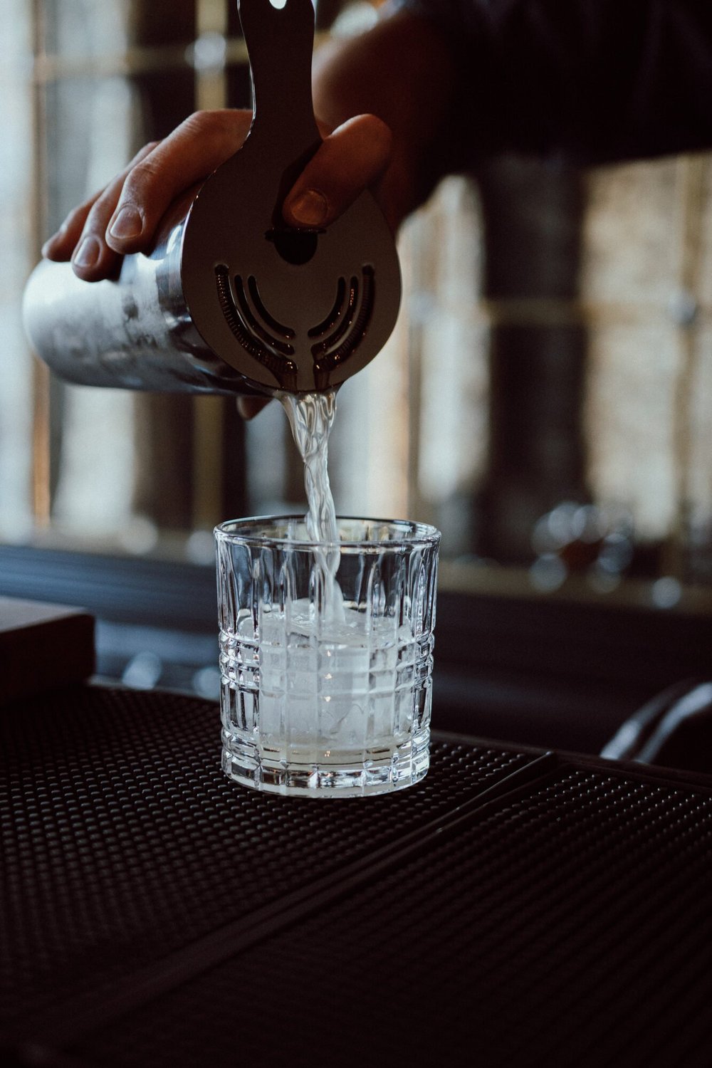 A cocktail being poured at the bar