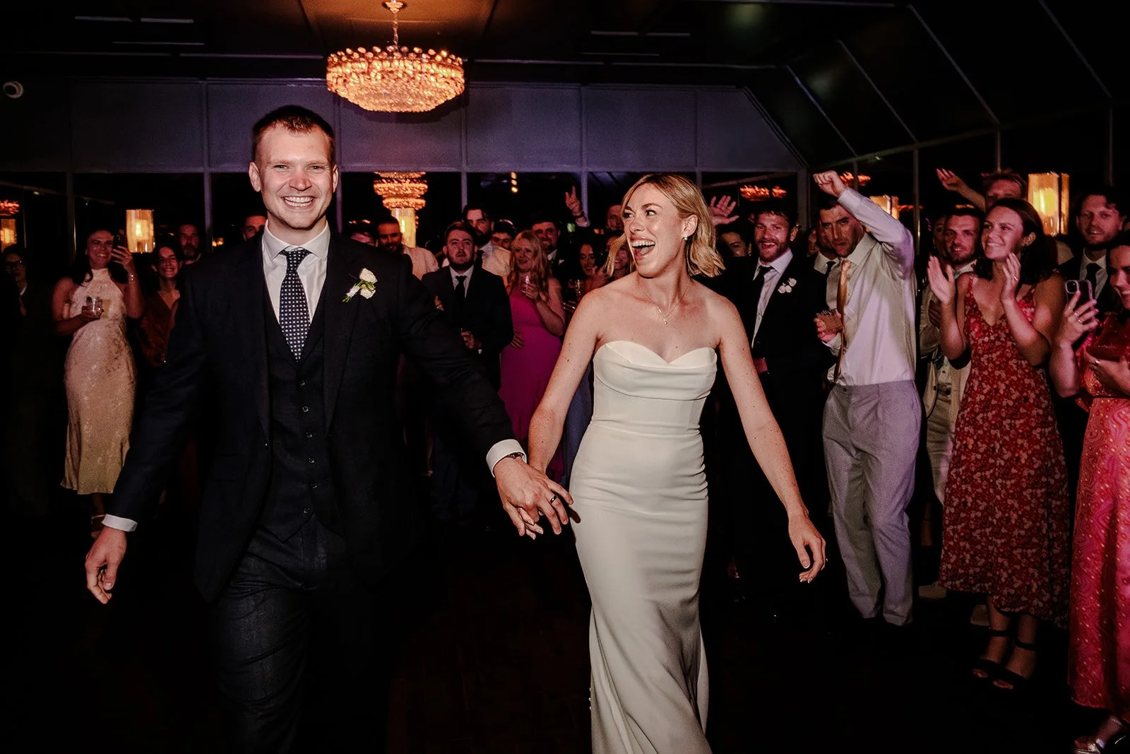 Jack and Abi making their entrance to the evening reception at Limekiln — huge smiles, guests going absolutely wild around them