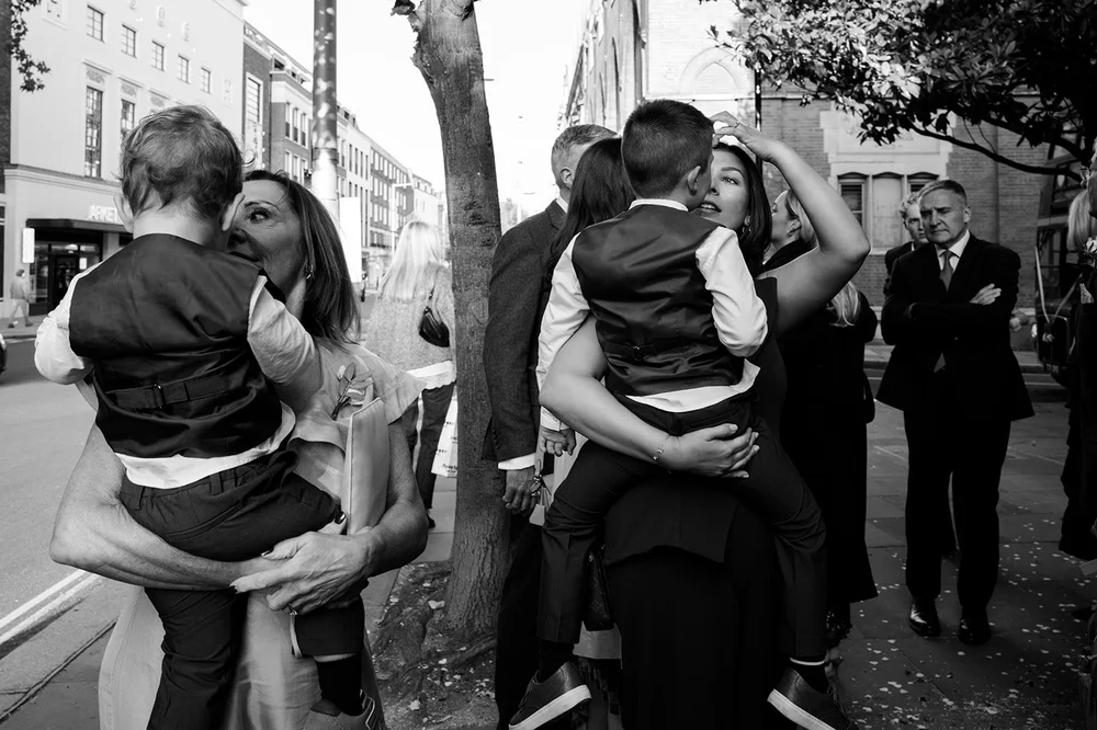 Bride and groom under the plane trees outside Chelsea Old Town Hall on the King&rsquo;s Road