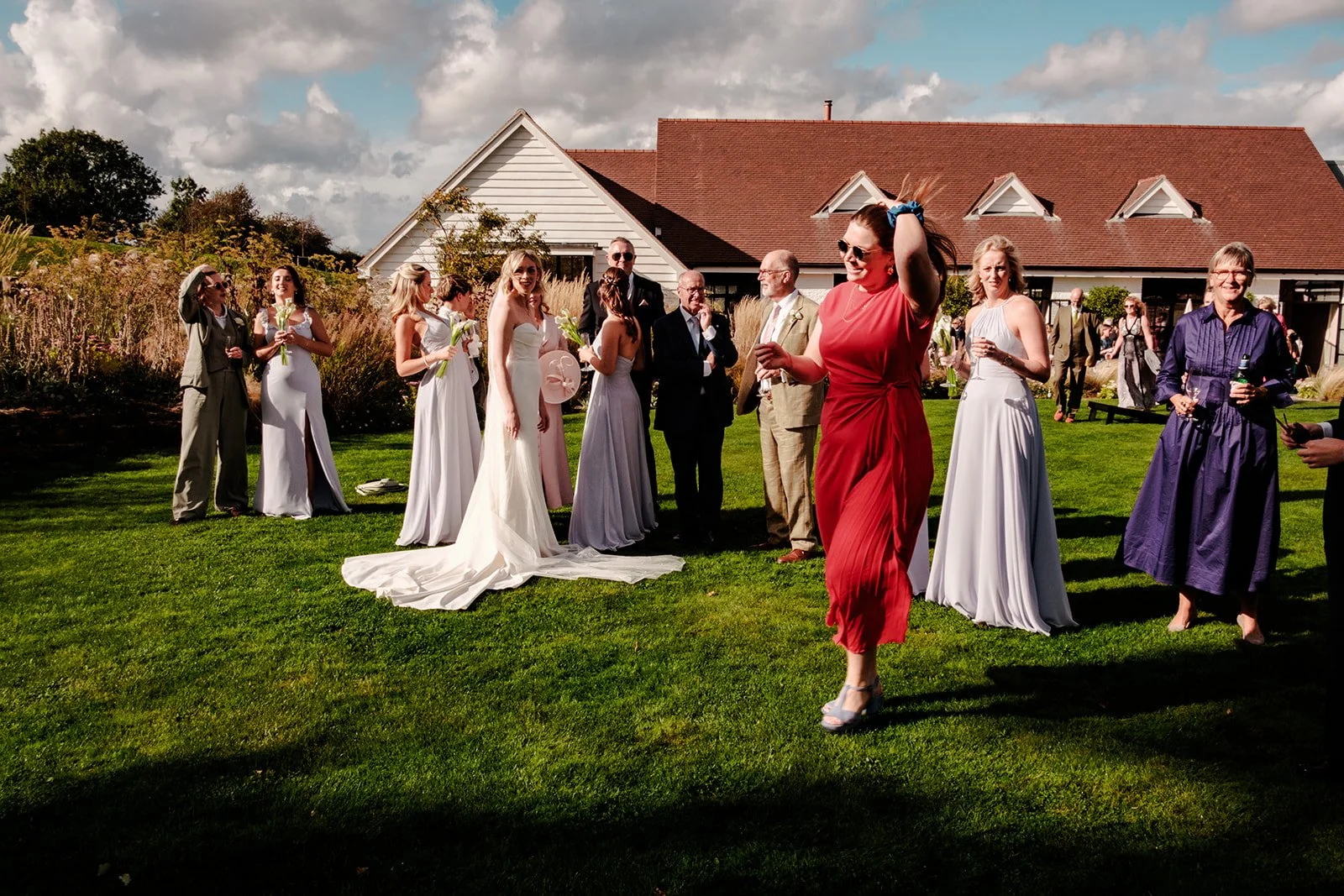 Abi and the bridal party with wedding guests on the lawn at Limekiln, the East Sussex venue building and beautiful grounds in the background