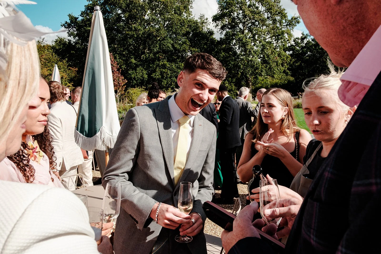 Wedding guest laughing with sheer delight, champagne glass in hand, during the outdoor drinks reception at Limekiln