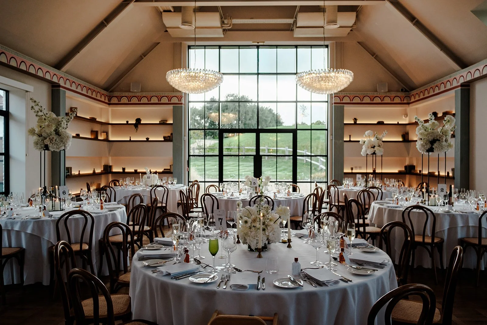Another angle of the beautifully set Limekiln reception room — elegant chandeliers reflecting in the tall windows overlooking the East Sussex countryside