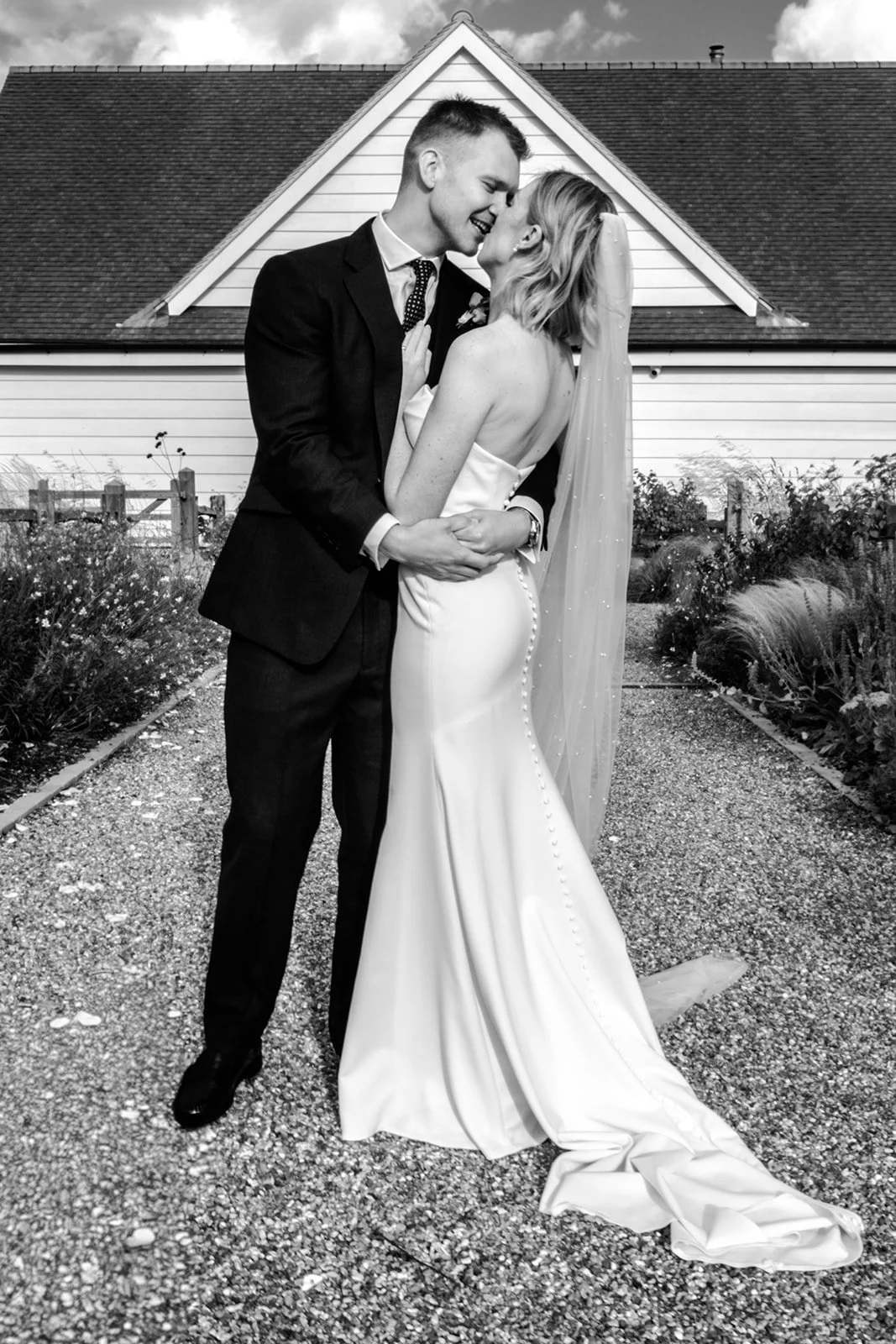 Jack and Abi embracing and laughing together outside the Limekiln barn — classic black and white wedding portrait